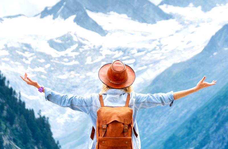 Woman with arms outstretching to the view of snow covered mountains