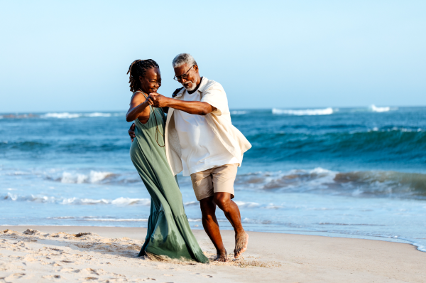 A couple dancing on the white beach with ocean behind them