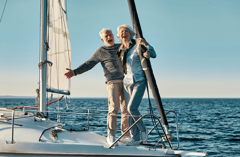 An older couple enjoying a peaceful moment together on a sailboat, surrounded by calm waters and clear skies