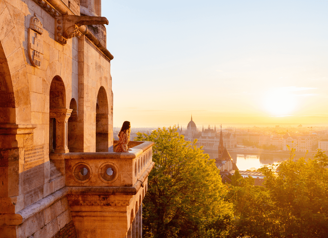 A woman relaxes on a balcony, enjoying a panoramic view of the city skyline.