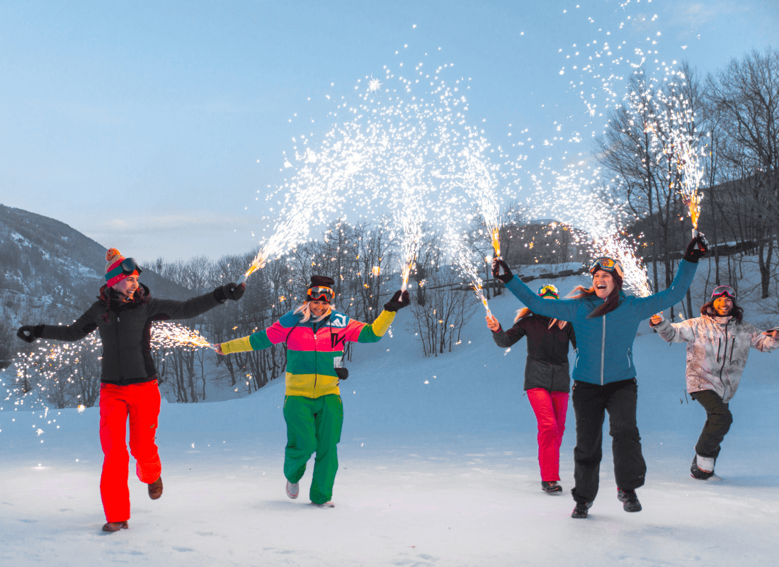 Four people playing with sparklers in the snow