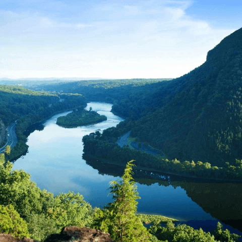 View of a river surrounded by mountains with vegetation, with a clear sky in the background