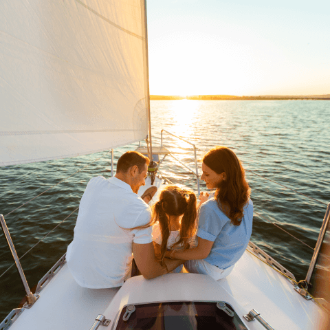 Two adults and a child sitting in a boat at sea