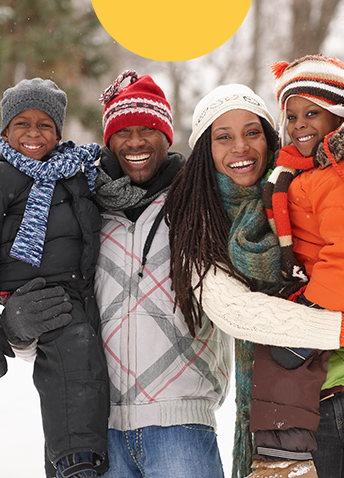 Man, woman and two children smiling with snowy background