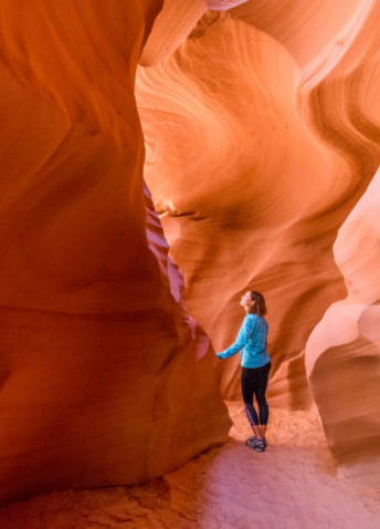 View of a person on a natural stone formation with sand on the ground